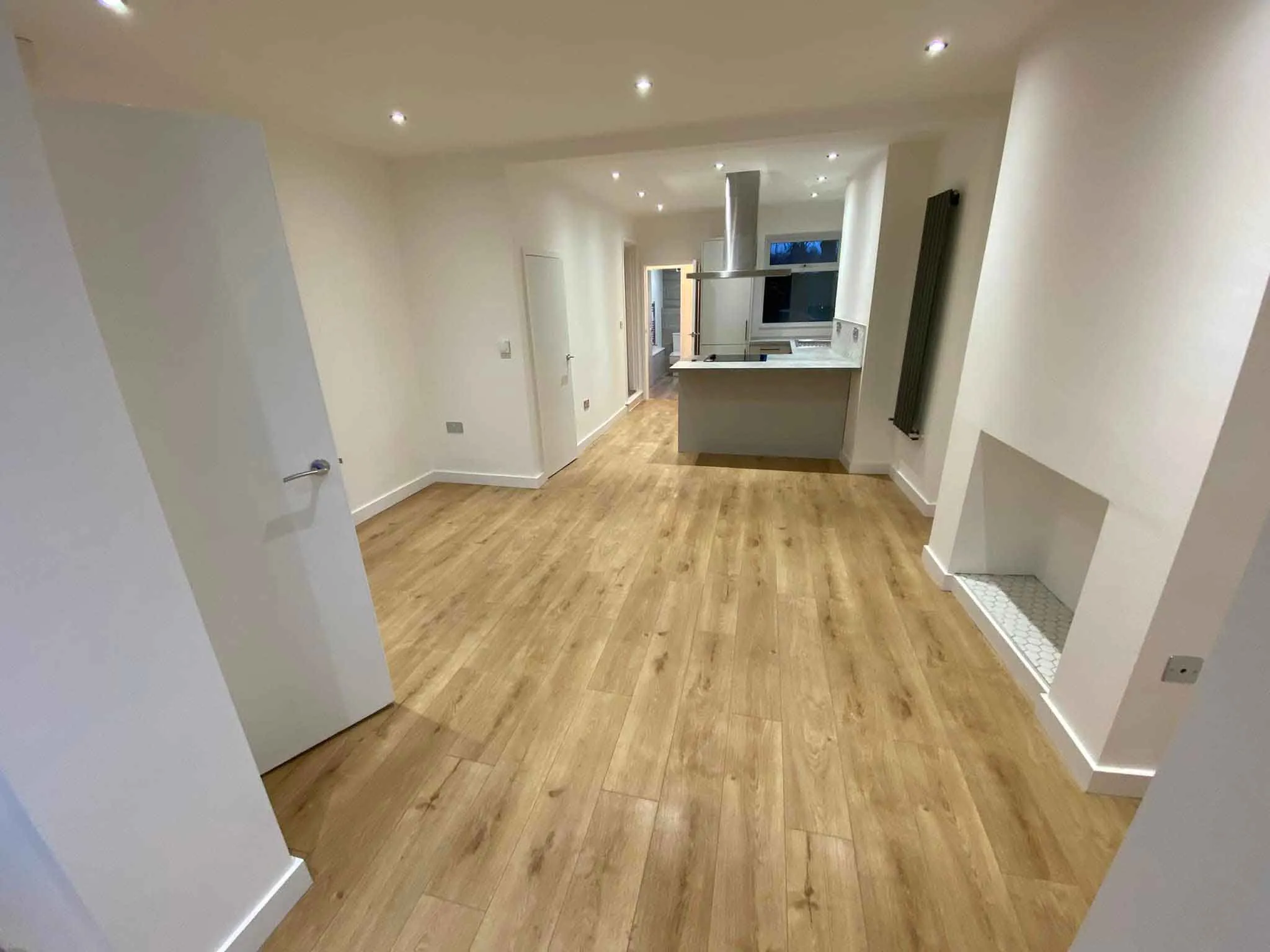 an empty living room with wood floors and white walls