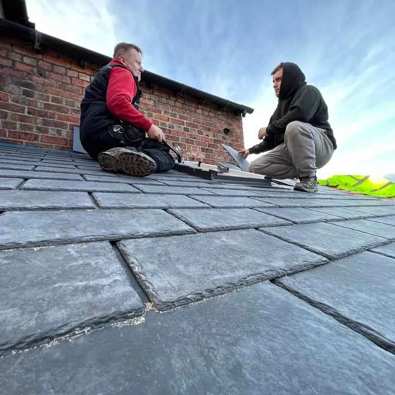 two men sitting on the roof of a house