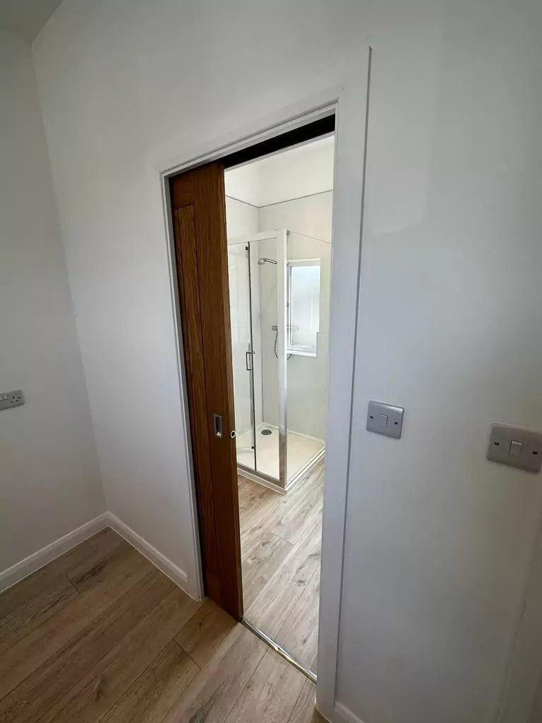 an empty room with a wooden door and white walls