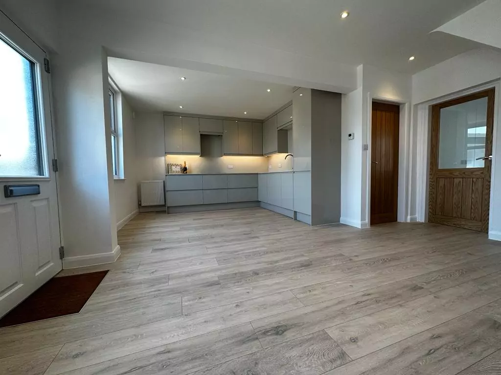 an empty living room with wood flooring and white walls
