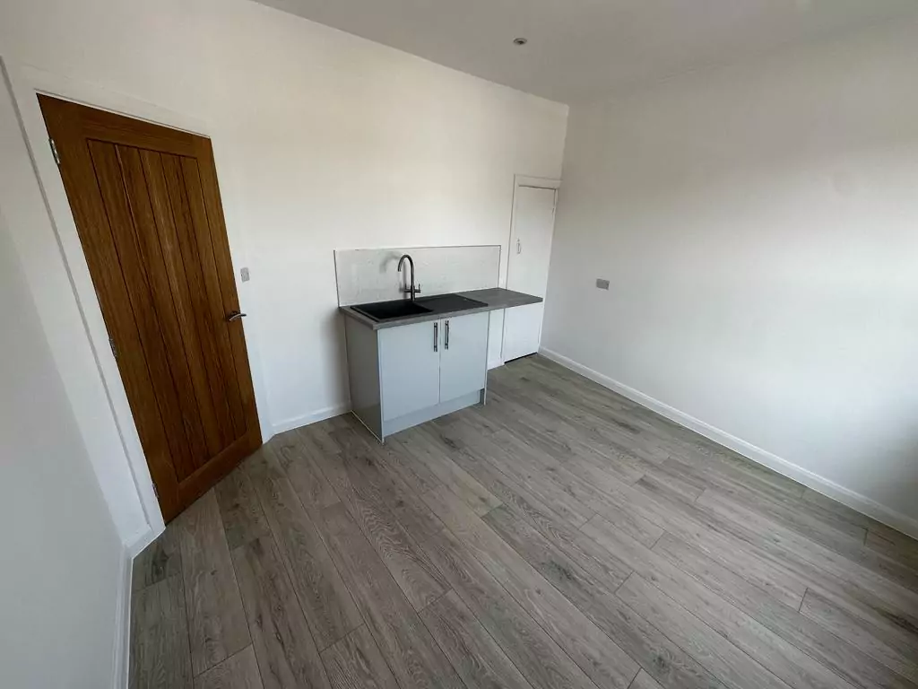 an empty room with a sink and a wooden door