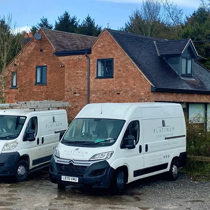 two white vans parked in front of a house